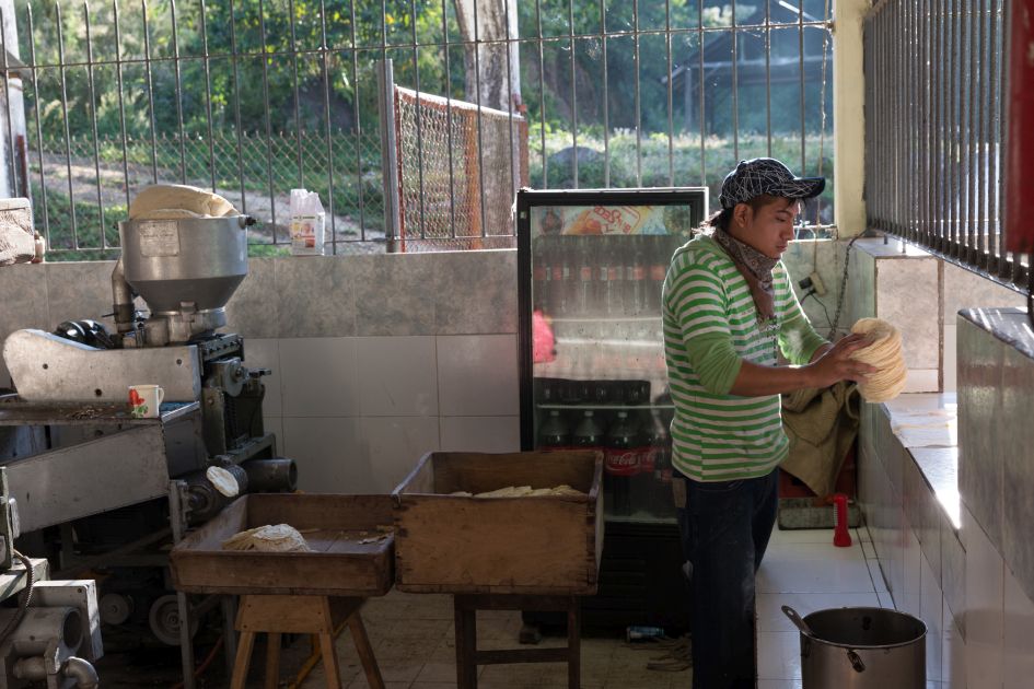 Tortillamaschine auf der Finca Hamburgo in Mexiko. Mitarbeiter hält einen Tortillastapel und gibt diese aus.